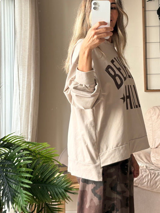 Sudadera Beverly Hills crema de perfil, más larga por detrás